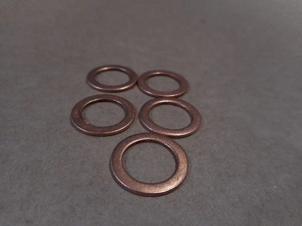 Runde Kupferdichtungen liegen auf einer flachen Oberfläche. Sie sind Teil von Remeha-Produkten zur Gewährleistung einer dichten Verbindung in Heizsystemen.